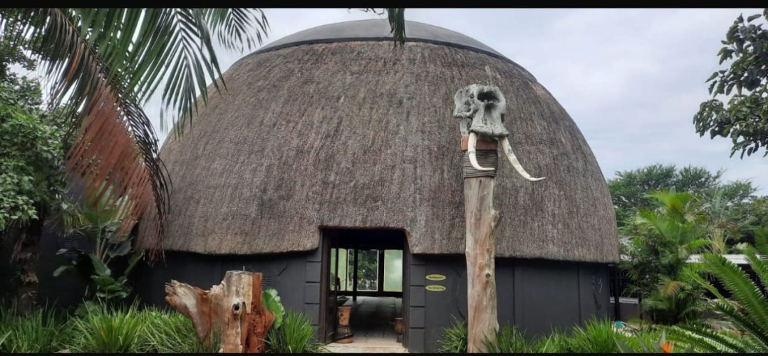 A large thatched dome with dark-stained walls and a landscaped entrance.