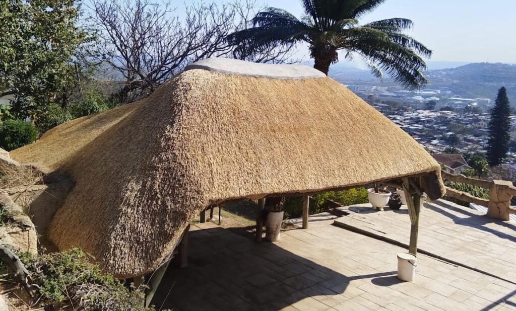 A sweeping thatched roof covering a deck with panoramic hillside views.