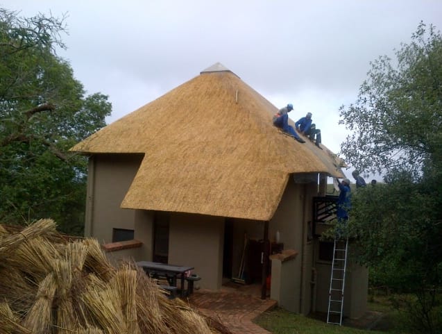 A steep thatched gable roof taking shape over the lodge structure.