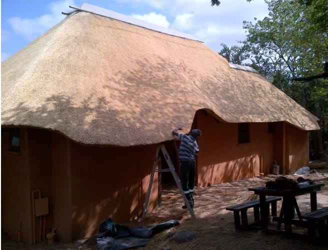 A thatcher trimming and finishing the roof edge for a clean, lasting result.