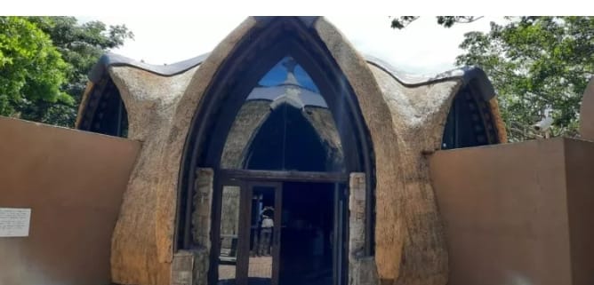 A striking curved thatch archway forming the lodge's main entrance.