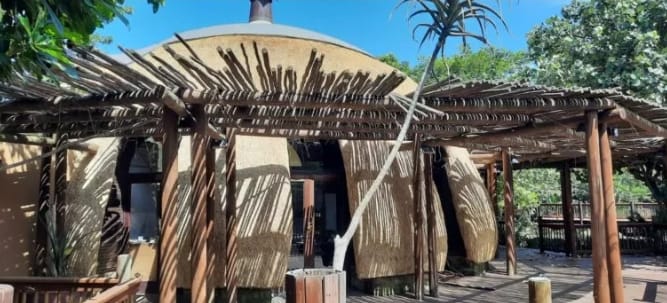 A thatched dome integrated with a timber pergola walkway.